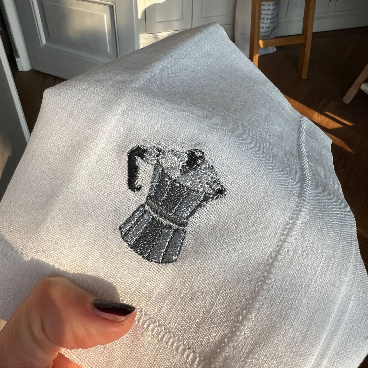 Detail embroidery of illustration by Stefanie Viëtor of Moka on white linen napkin with hemstich of 40x40cm